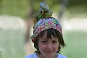 une petite fille avec un iguane sur la tête pour représenter le droit des enfants à être représenté